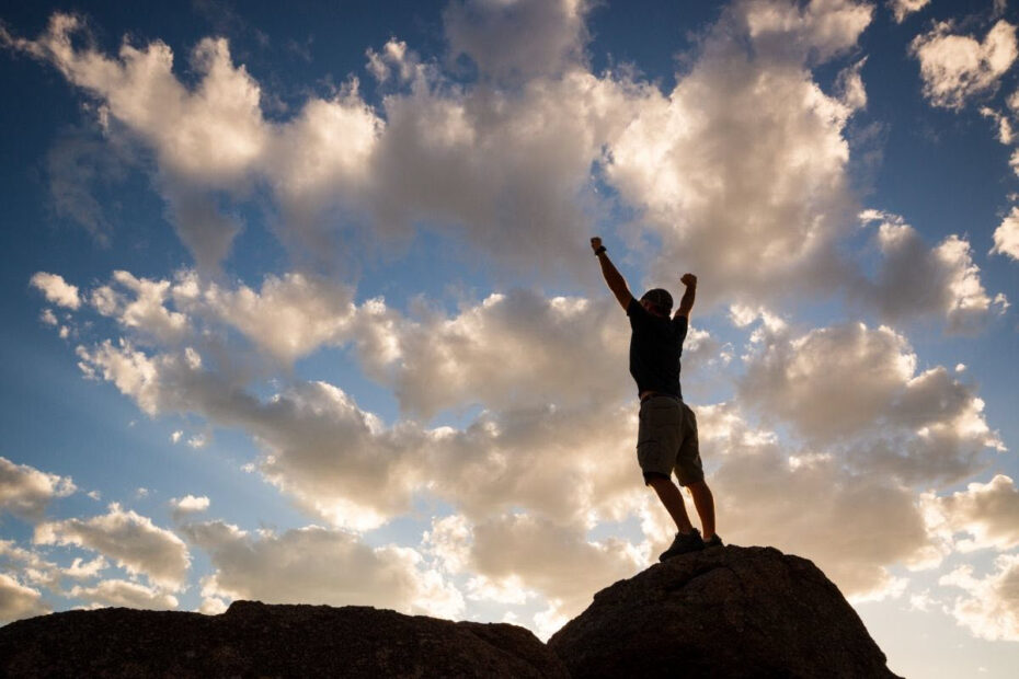 Silhouette of man standing with arms triumphantly raised